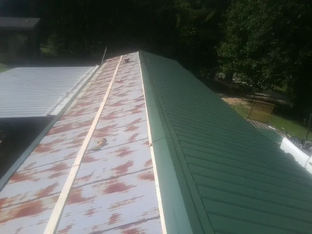 Old rusted panels beside newly installed green metal roofing — Wind Damage Roof Repair by Roofing Brothers in Semmes