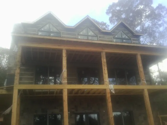 Dormers and porch framing on a large log home under construction — Roof Coating work by our crew in Semmes