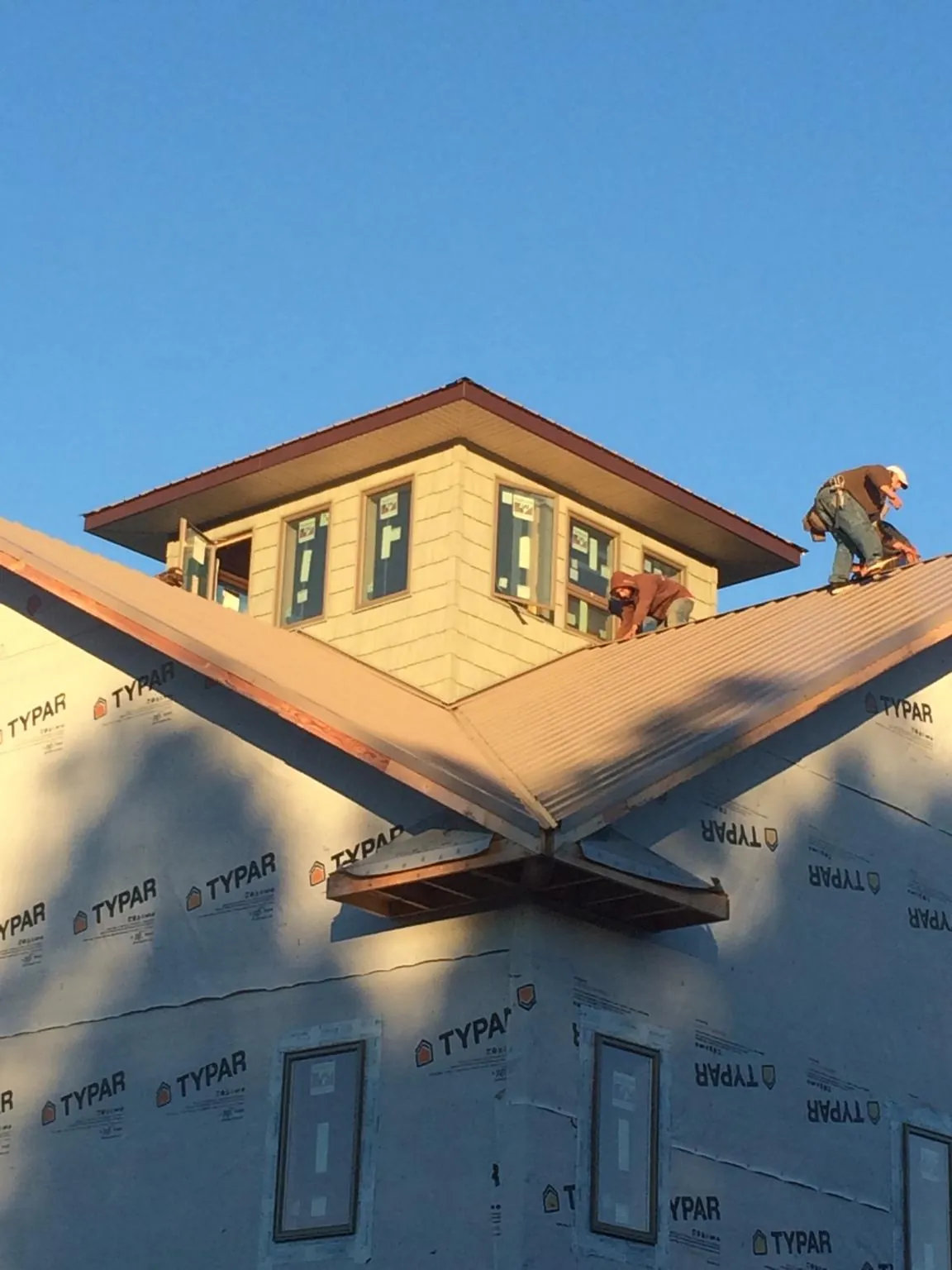 Roofers working around a rooftop cupola on a new metal roof at sunset — Roof Waterproofing in Semmes by Roofing Brothers